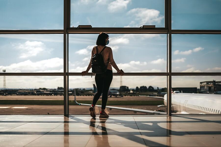 A woman looking out of a window at an airport.
