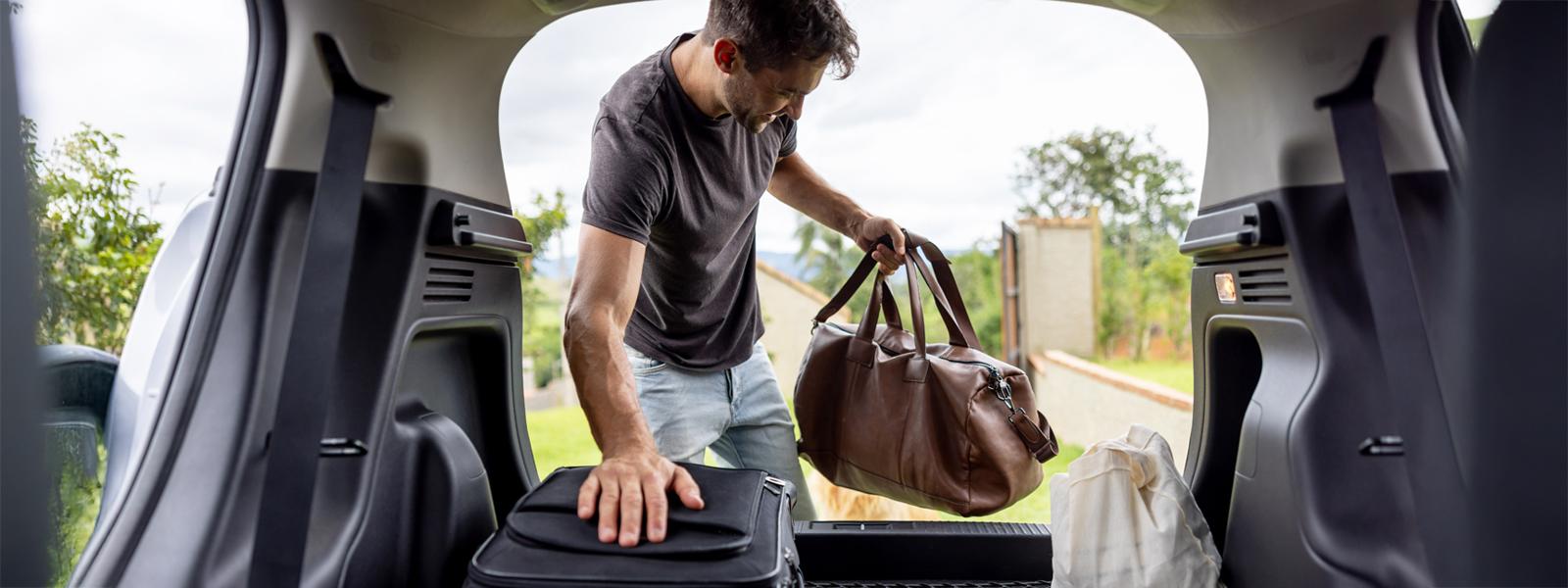 Man leaning into the backseat of a car loading luggage
