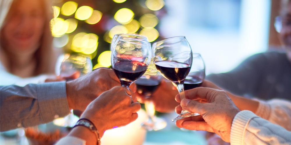 A group of people toasting with glasses of red wine in a festive setting.