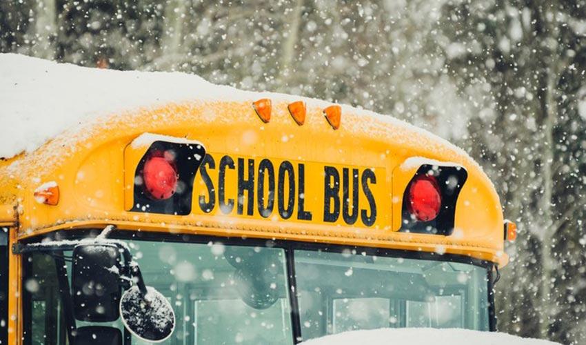 A yellow school bus covered in snow.