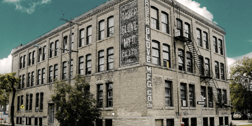A historic brick building with fire escapes on the facade on a sunny day.