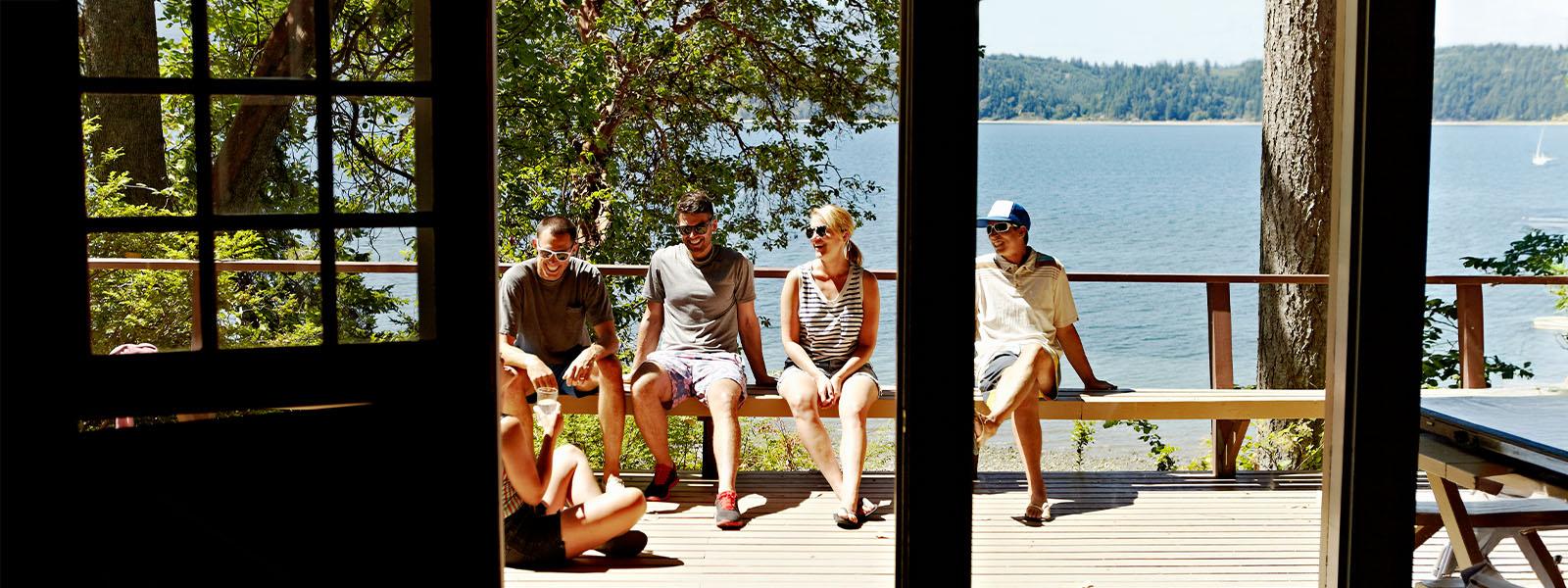A group of four adult friends sitting on a cottage deck.