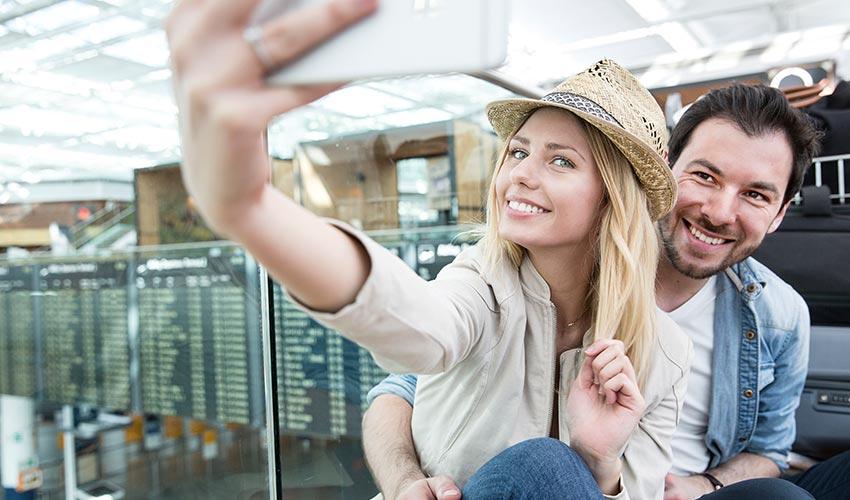 A man and woman taking a selfie at an airport.