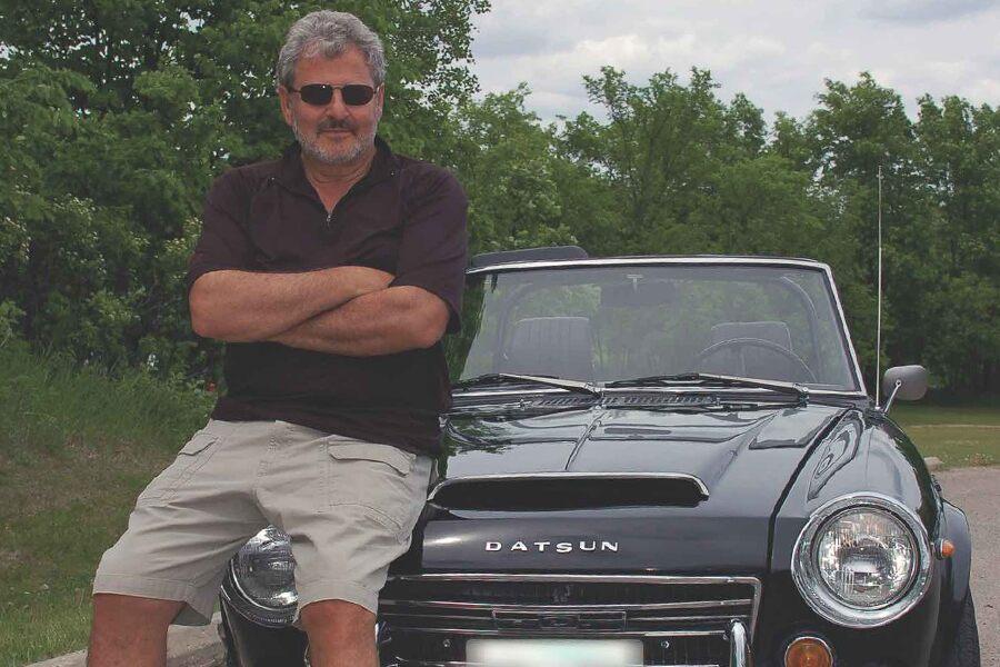 A man standing next to a black sports car.