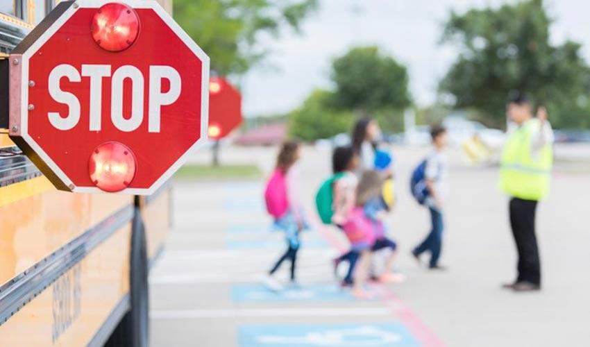 A group of children standing near a stop sign on a school bus.