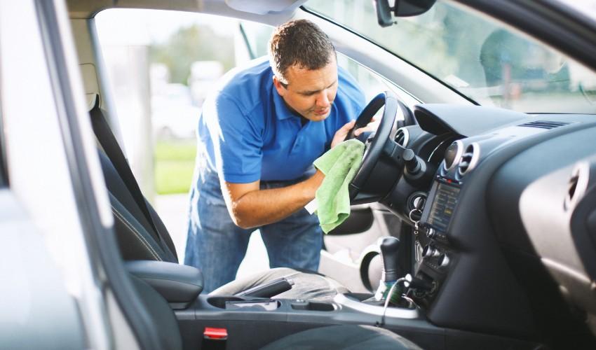 A man cleaning the steering wheel of a car.