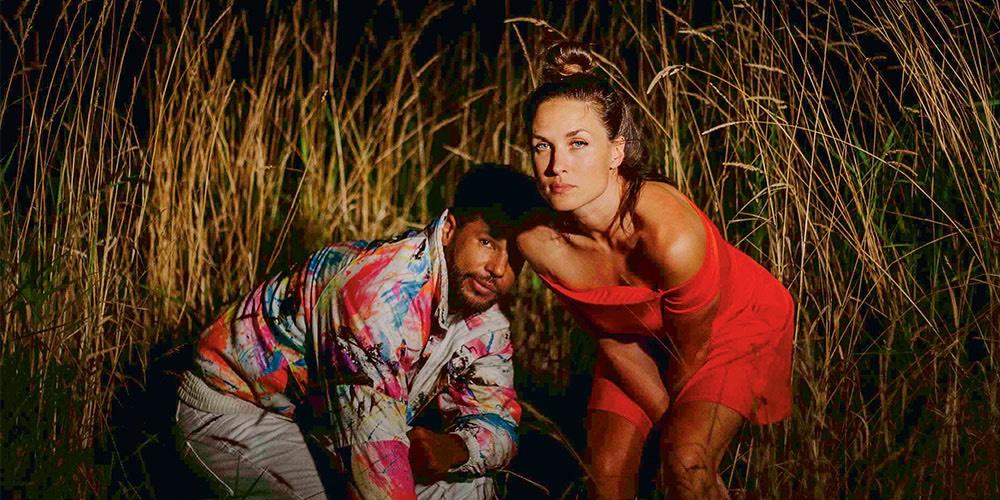 Two people crouching in a field at night, poised for action or surprise.