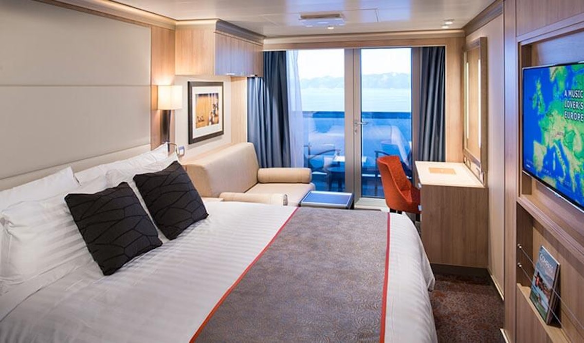 A room on a cruise ship with a bed and tv.