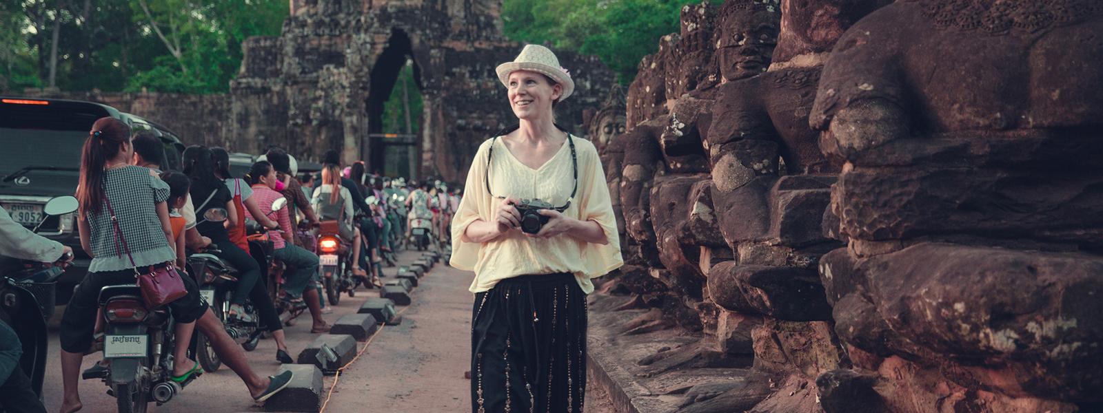 Female tourist with camera walking around a stone temple