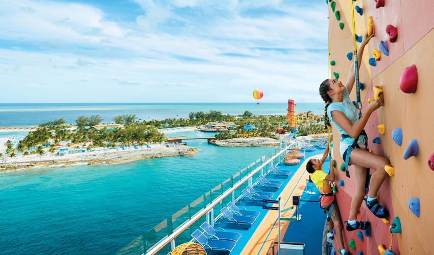 A woman climbing a rock wall on a cruise ship.