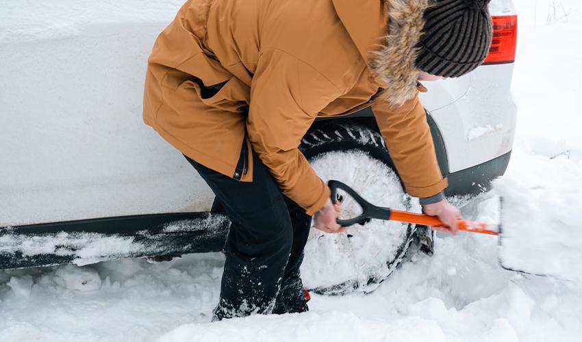 A person shoveling snow with a car tire.