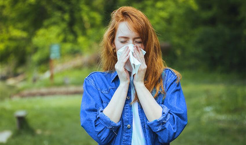 A woman blowing her nose with a tissue.