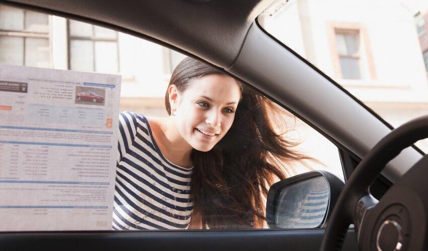 A woman in a car holding a paper in her hand.