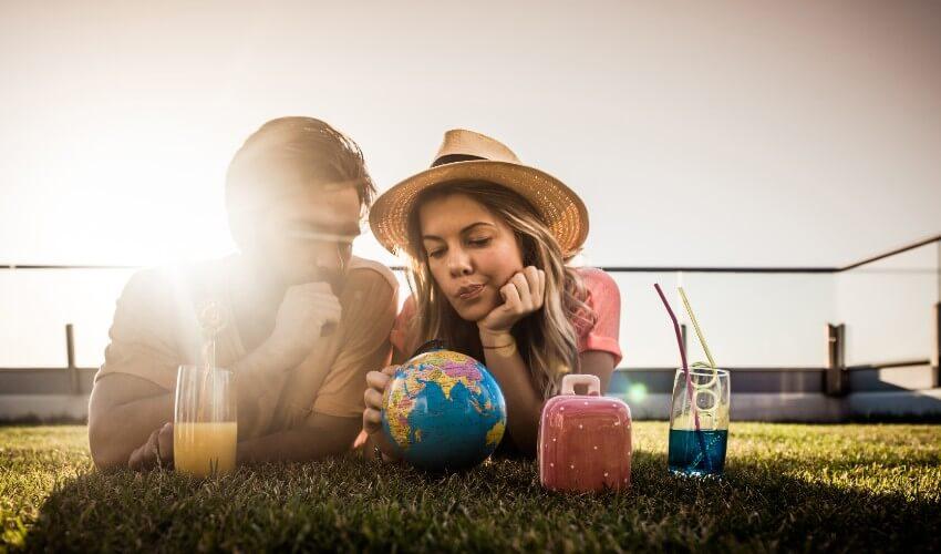 A couple looking at a globe on the grass.