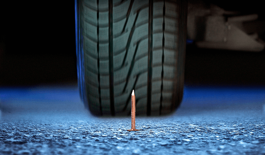 A tire with a nail sticking out of it.