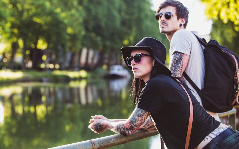 A couple leaning on a bridge overlooking a river.