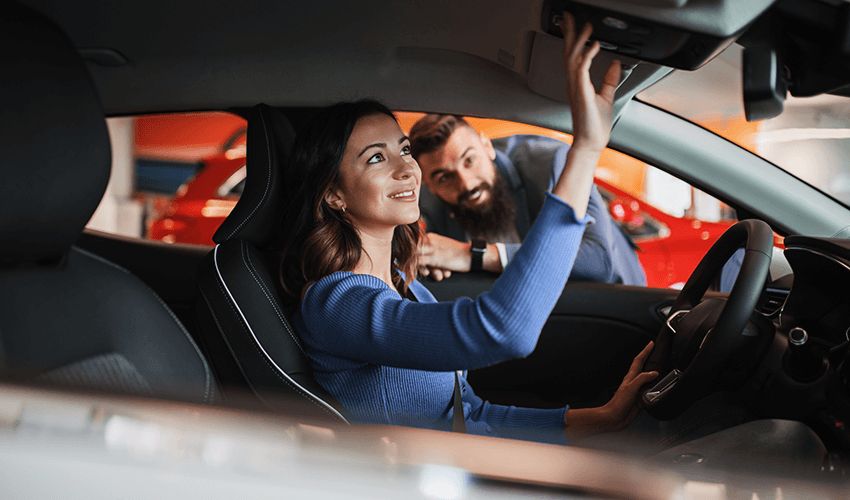 A man and woman in a car showroom.