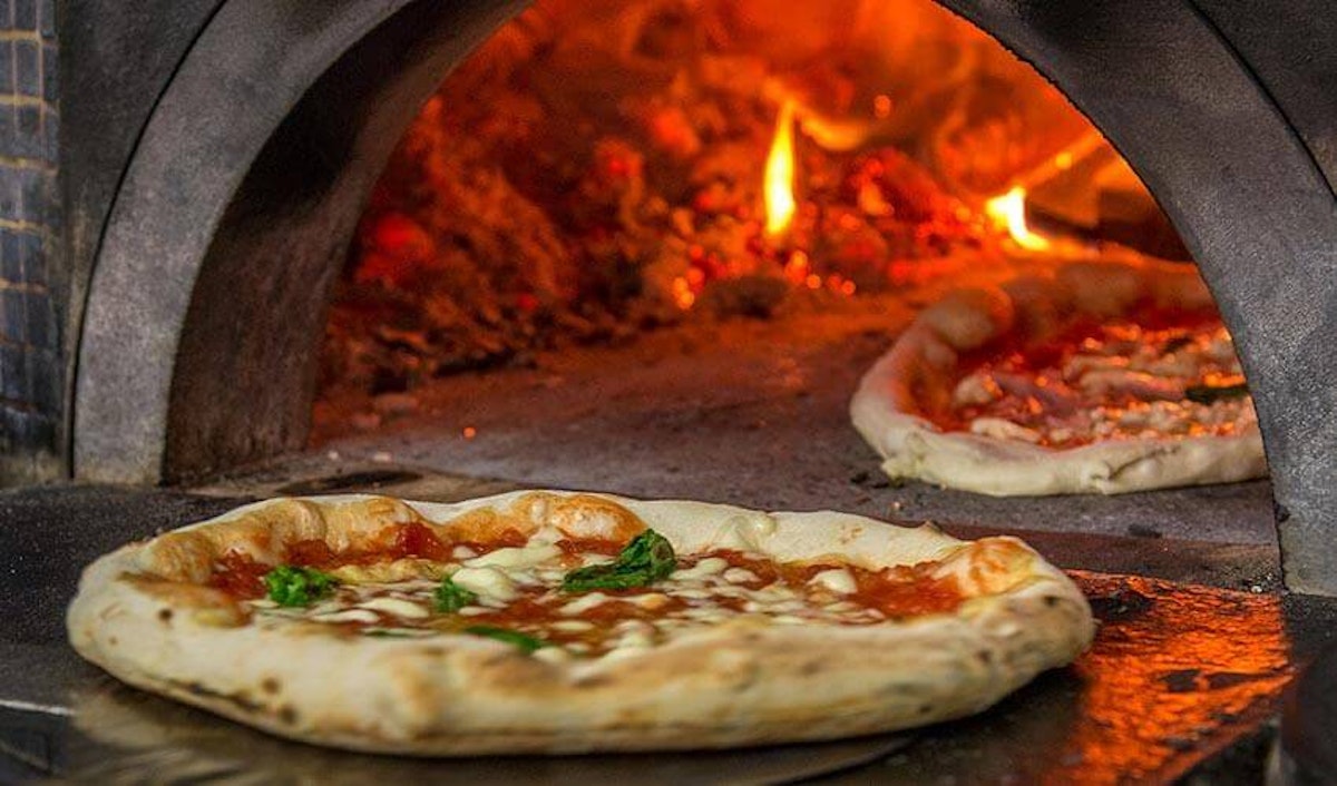 A pizza is being cooked in a wood fired oven.