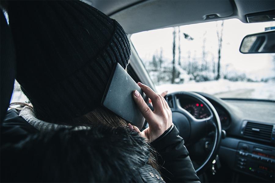 A woman talking on a cell phone in a car.
