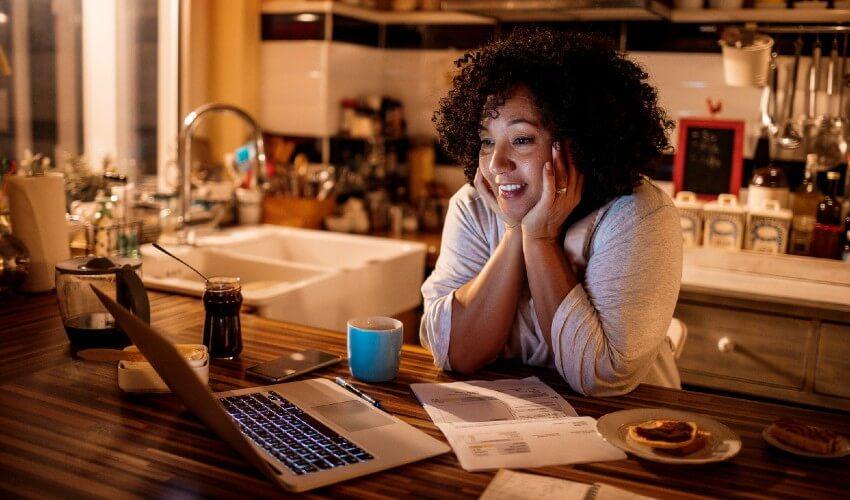 A woman working on her laptop in the kitchen.