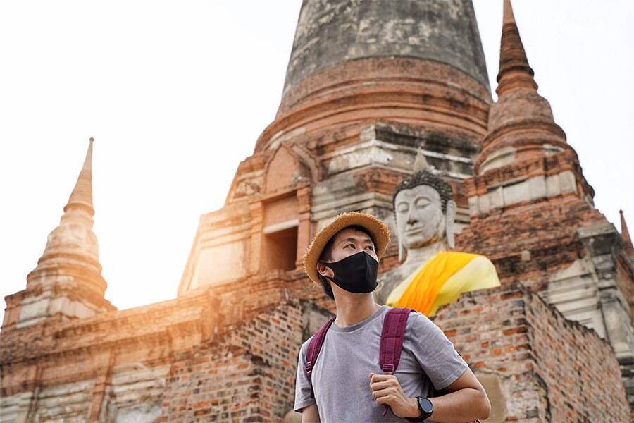 A man wearing a black face mask in front of a statue.