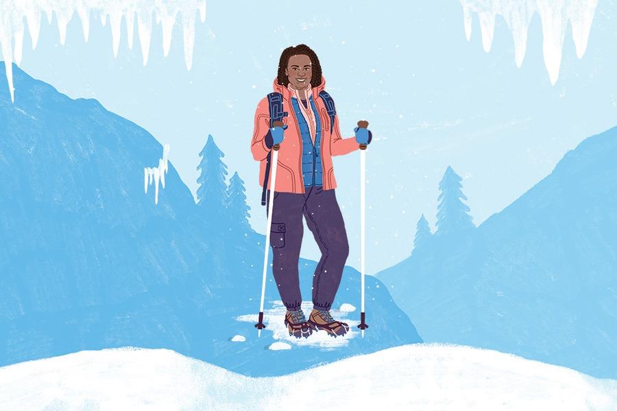 A smiling female hiker with trekking poles standing on snow-covered ground with icy cliffs and fir trees in the background.