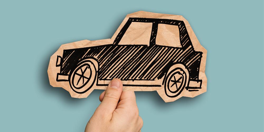 A hand holding up a paper with a car drawn on it.