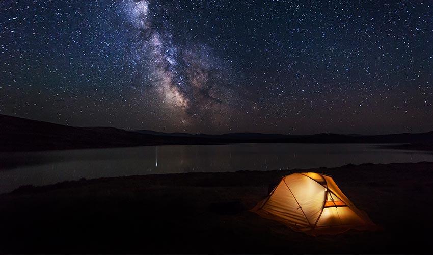 A tent lit up under the milky way.