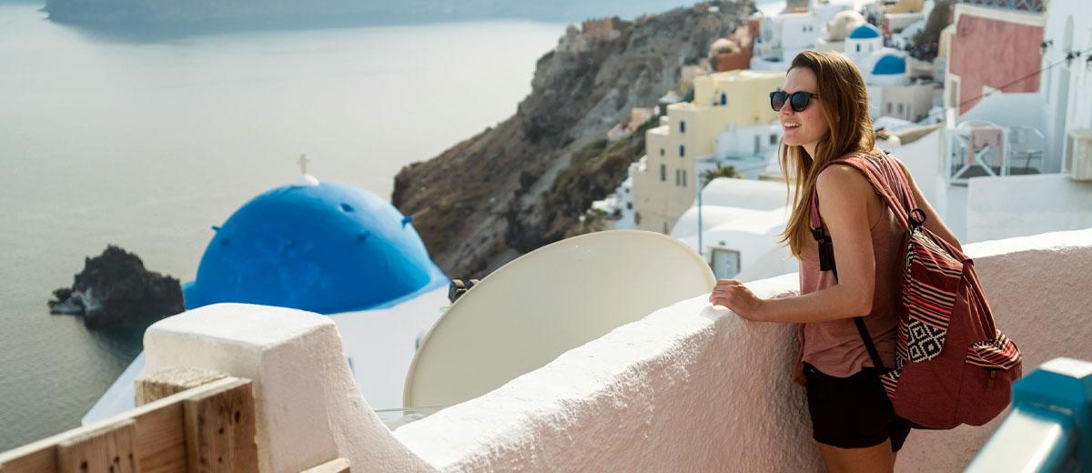 A woman standing on a balcony, looking at an ocean view.