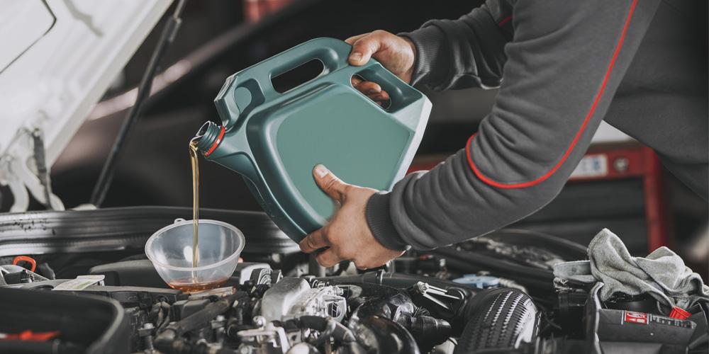 A man pouring oil into a car engine.