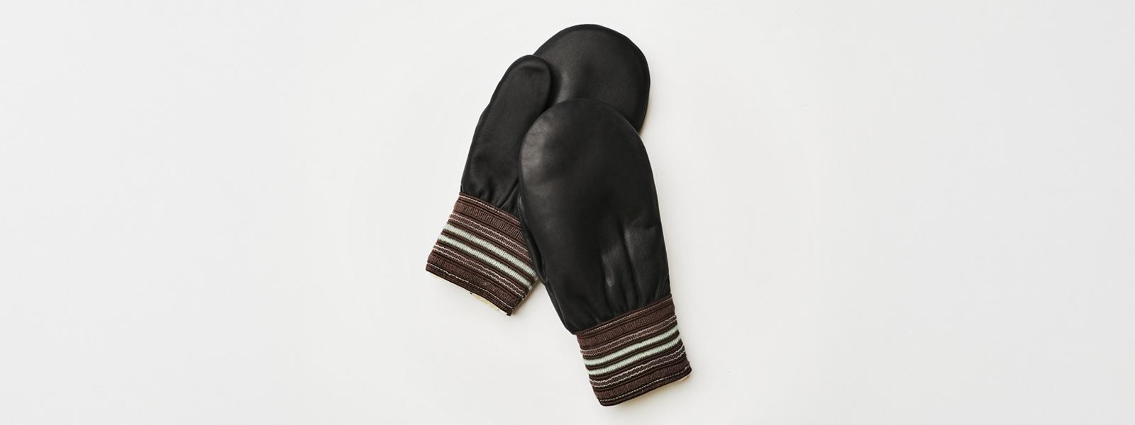 A pair of black, leather mittens on a white surface.
