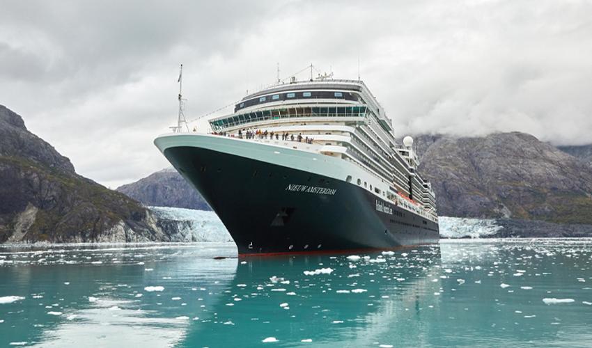 A large cruise ship in the water near a mountain.