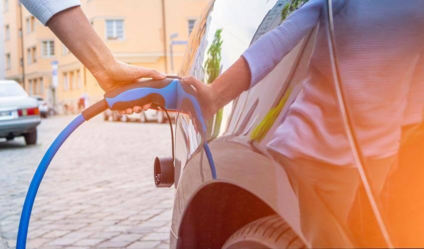 A person is charging a car with a blue hose.