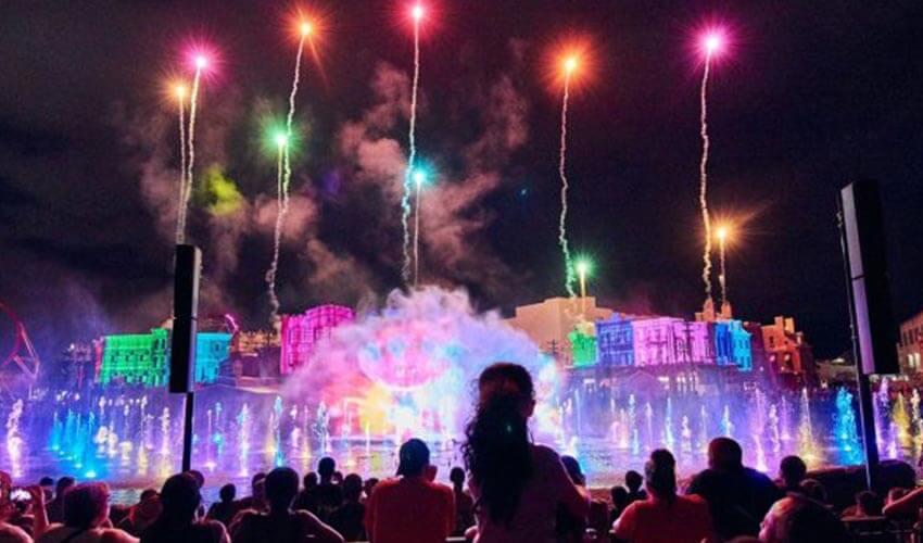 A crowd of people watching fireworks at night at disneyland.