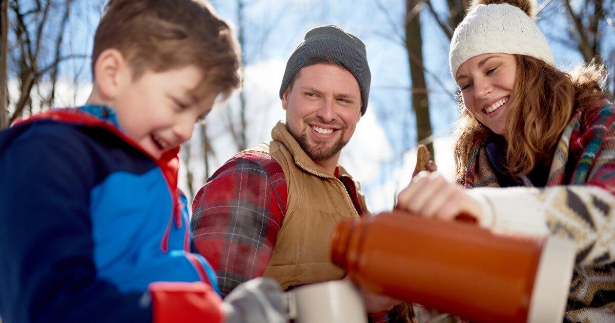 A family is holding a water jug in the snow.