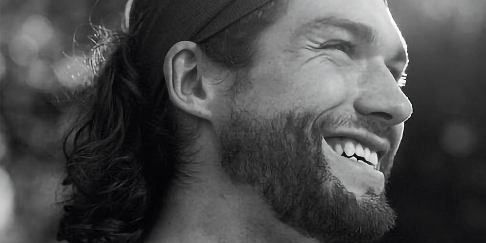 Man with a headband smiling in black and white.