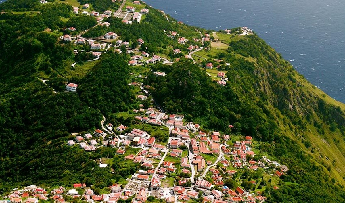An aerial view of a small town on a hill overlooking the ocean.