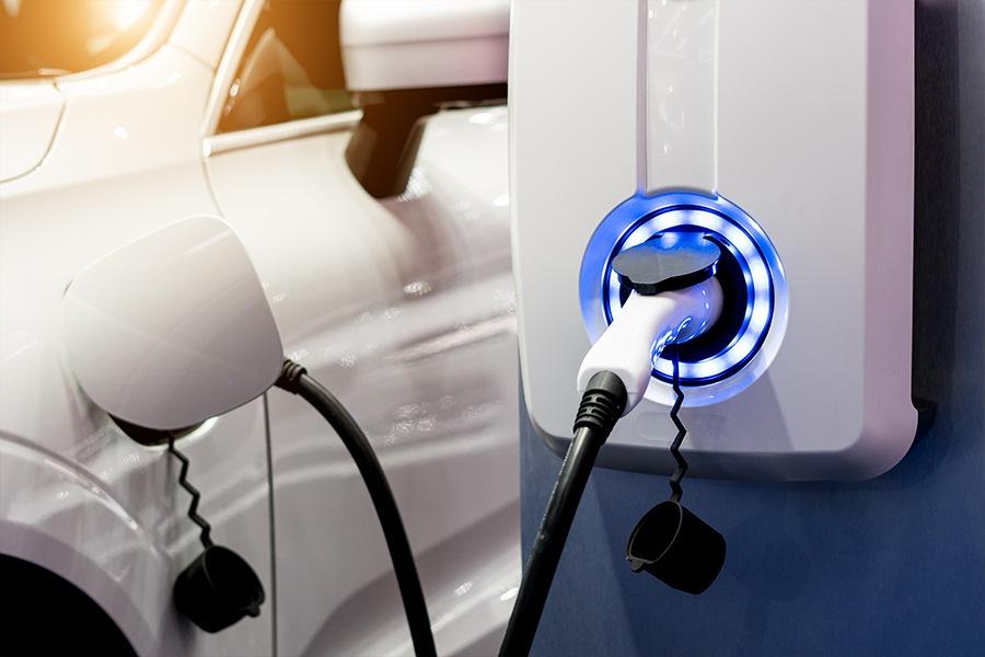 A white car is plugged into an electric charger.