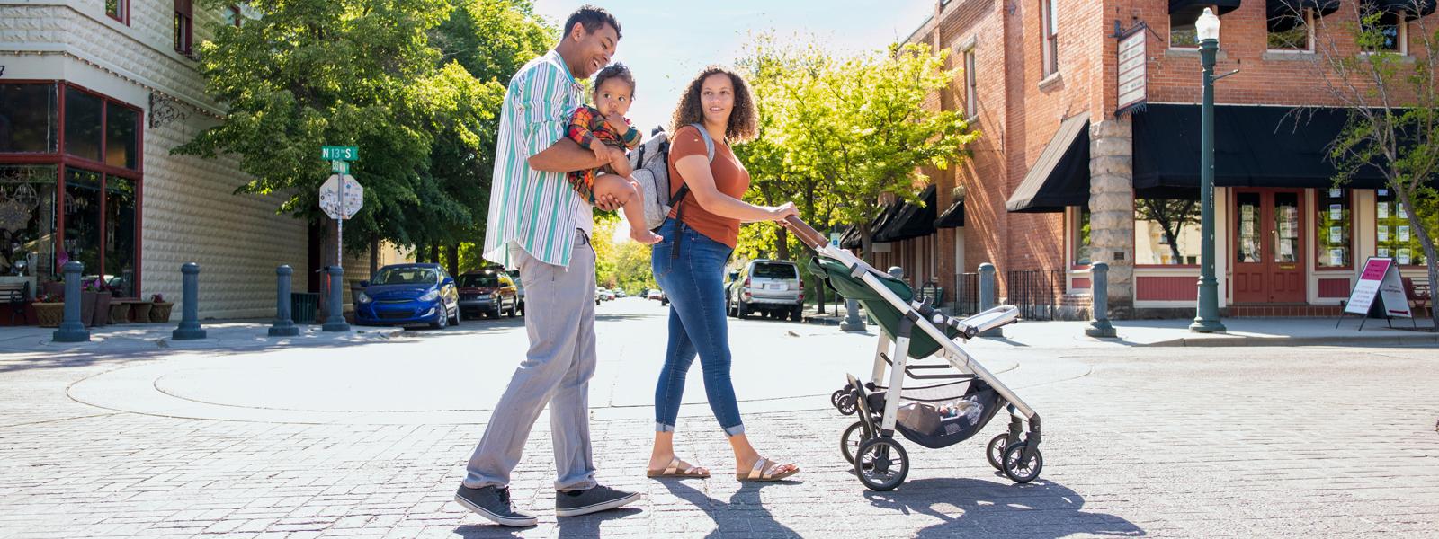 Family of three walking with a stroller outside.