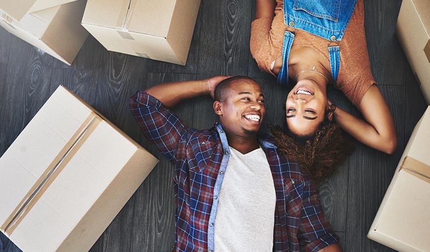 A couple laying on the floor with moving boxes in the background.