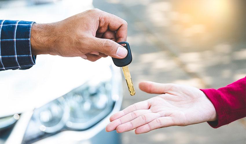 A person handing a car key to another person.