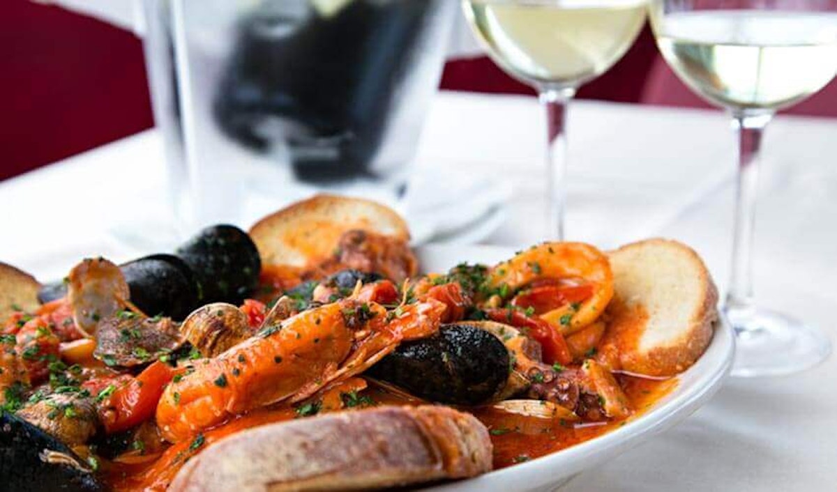 A bowl of seafood and wine on a table.