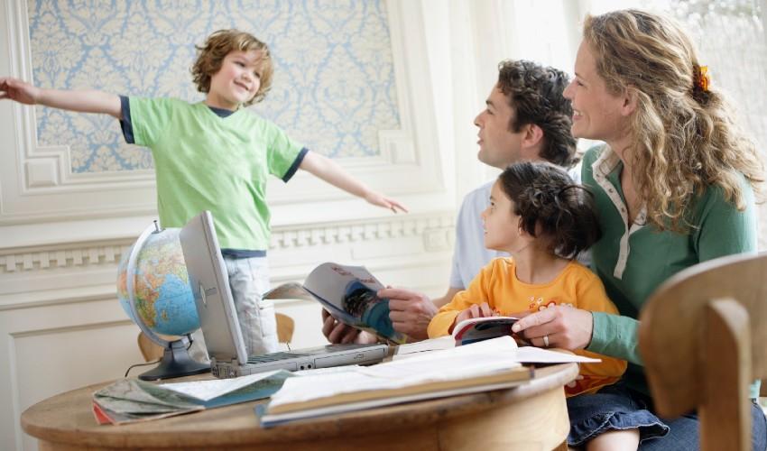 A family is sitting at a table with a laptop.