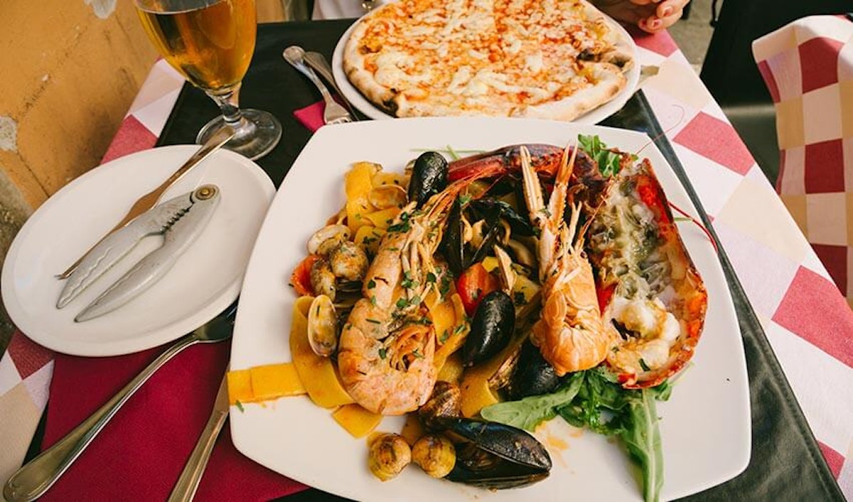A plate of seafood and pizza on a table.
