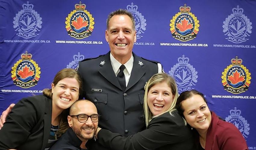A group of people posing for a photo with a police officer.