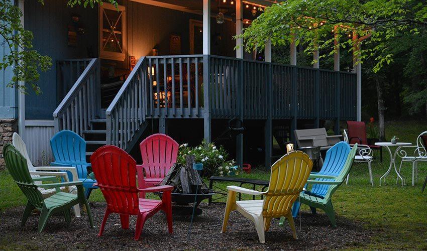 A group of colorful adirondack chairs in front of a house.