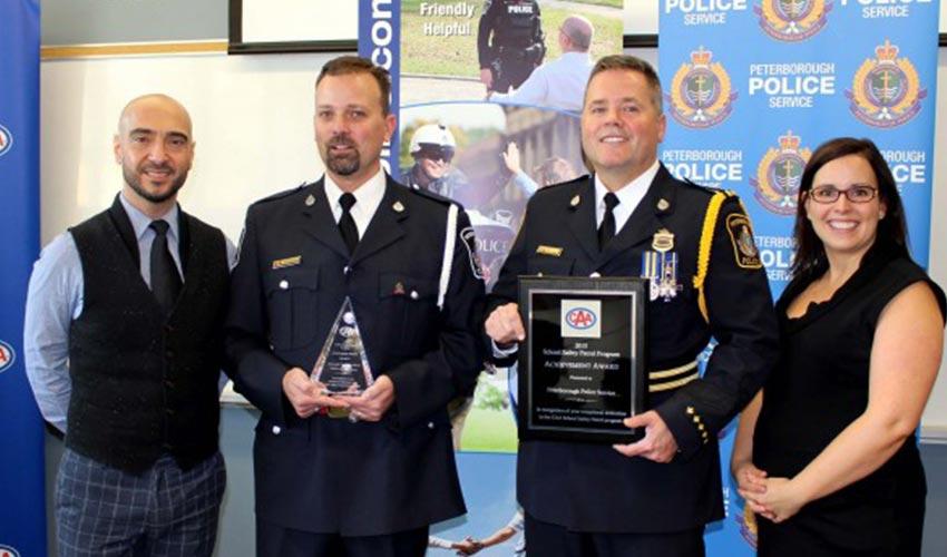A group of police officers holding an award in front of a poster.
