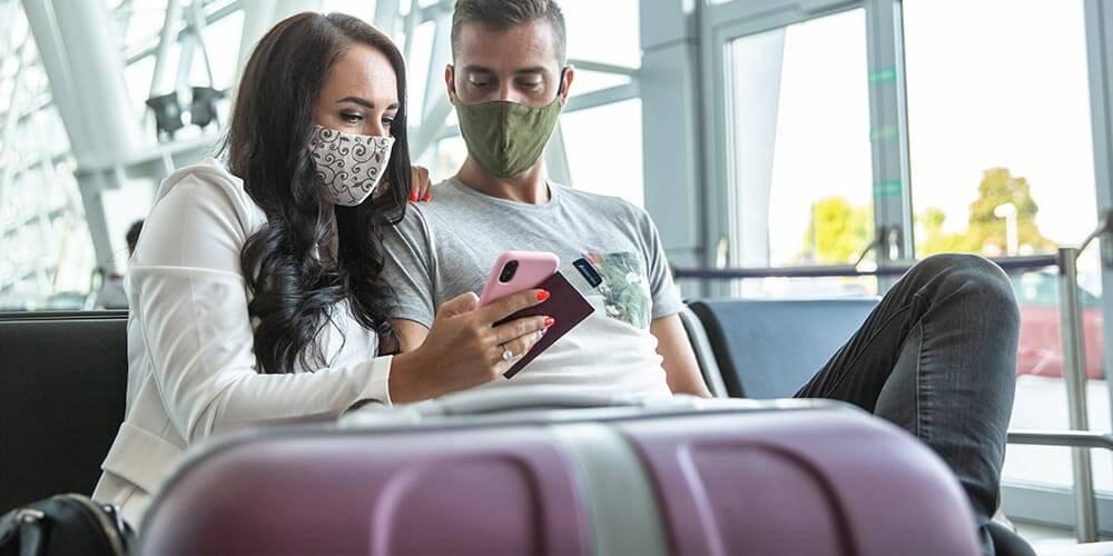A man and woman wearing face masks at an airport.