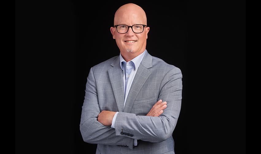 A bald man wearing glasses and a suit is posing for a photo.