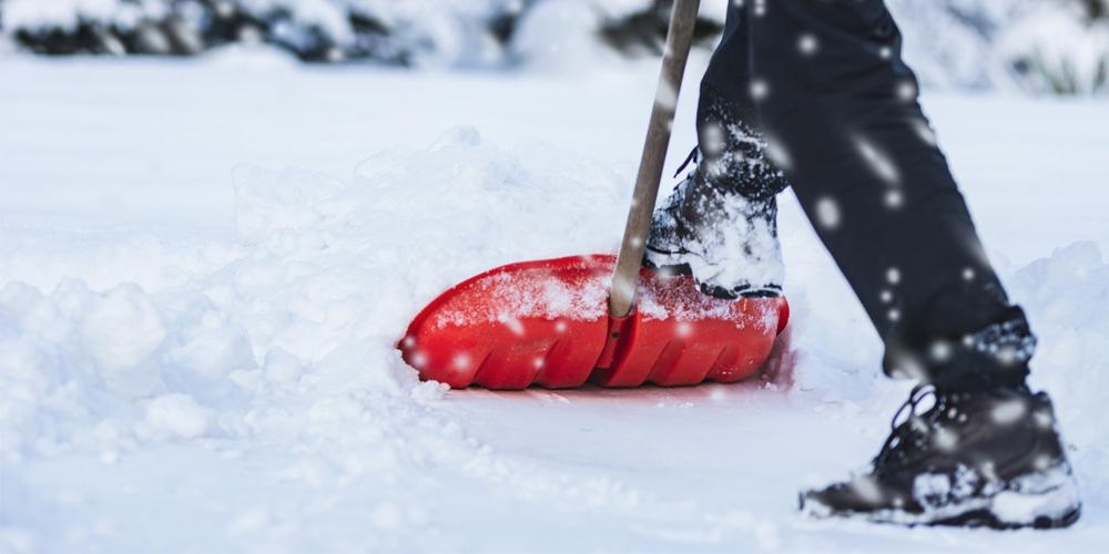 Shoveling snow with a red plastic shovel.